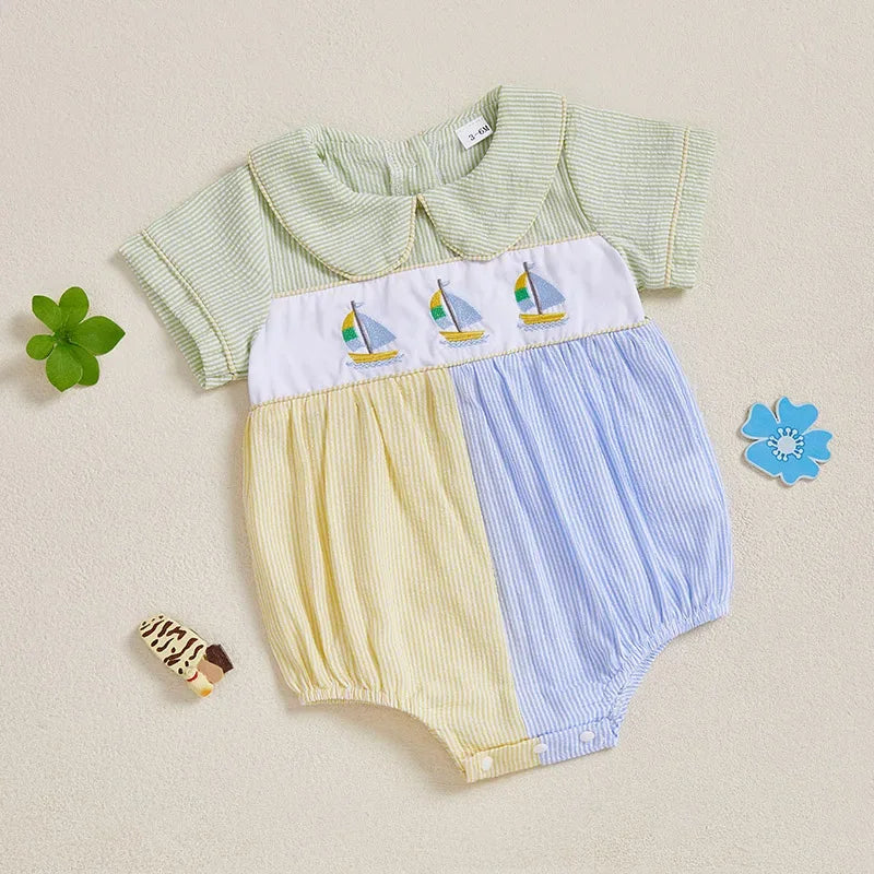 Baby seersucker romper with sailboat embroidery and Peter Pan collar, green top, white panel, yellow-blue blocks.