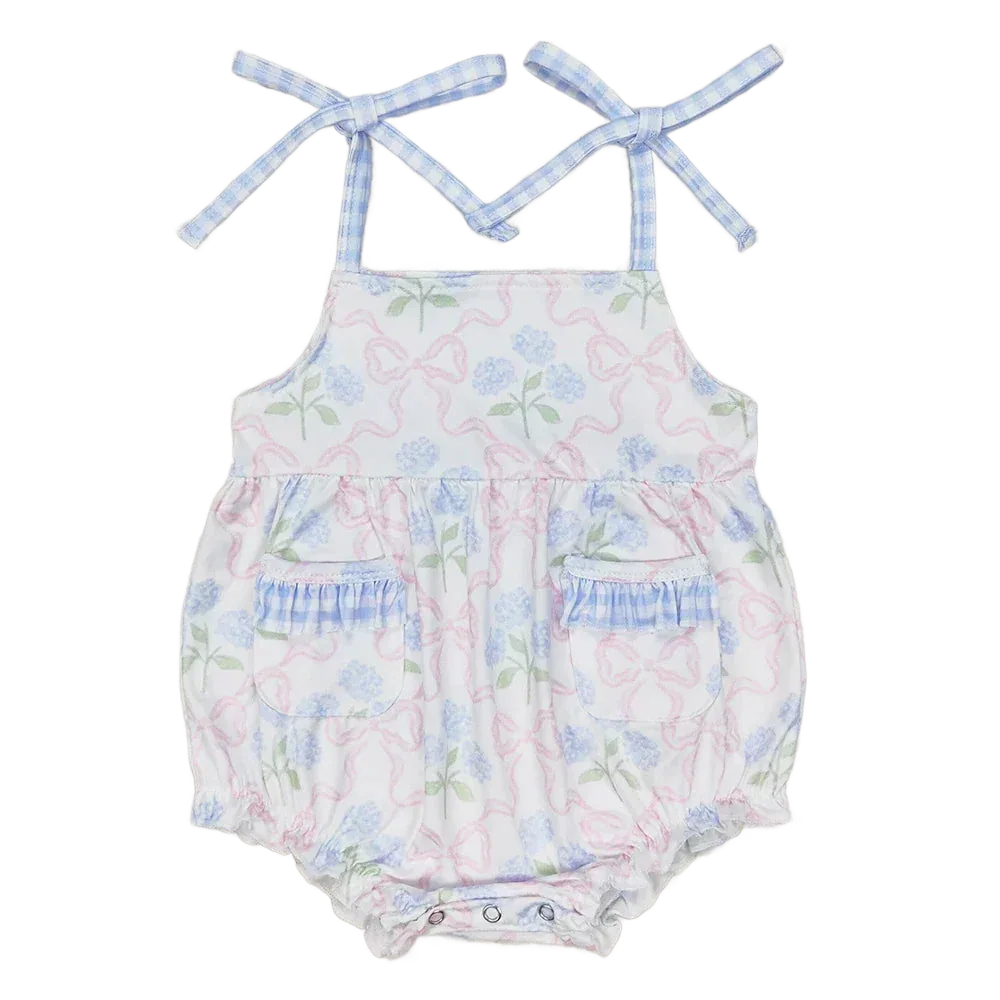 baby sunsuit with blue floral and pink bow print, adjustable tie straps, pockets, and ruffle details