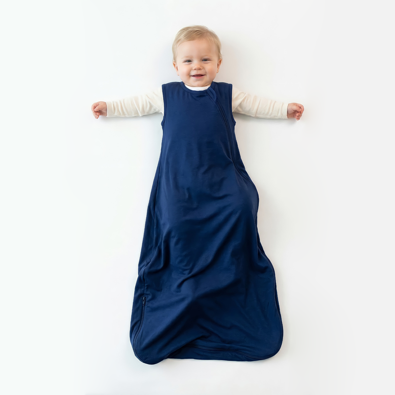Baby wearing navy blue cooling bamboo sleep sack over cream shirt