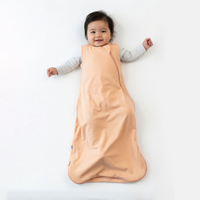 Baby wearing peach bamboo sleep sack over grey shirt