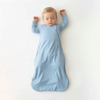 Toddler in light blue bamboo sleep sack lying on back with arms raised