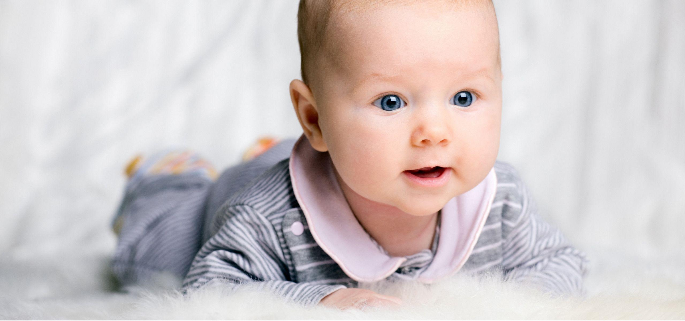 Baby wearing a striped shirt and pink collar against a white background