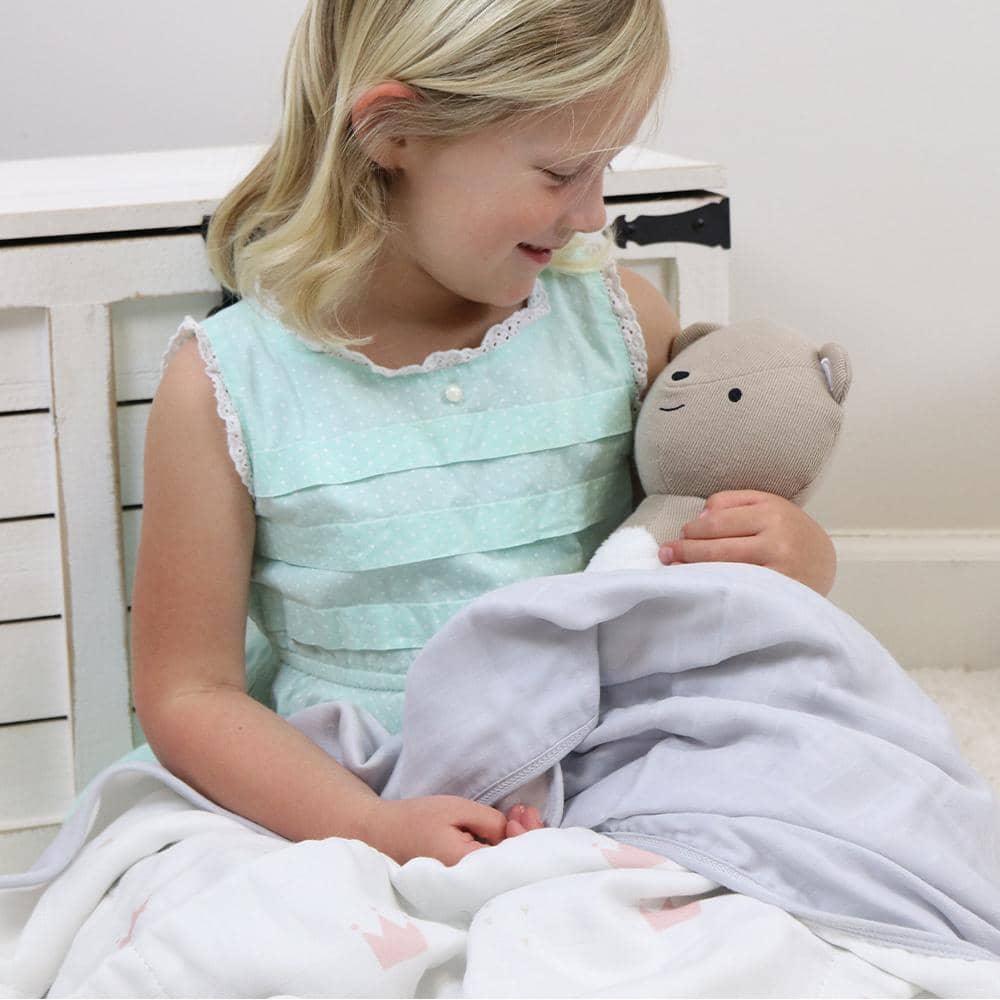 Light gray bamboo muslin baby blanket held by a child with a stuffed bear