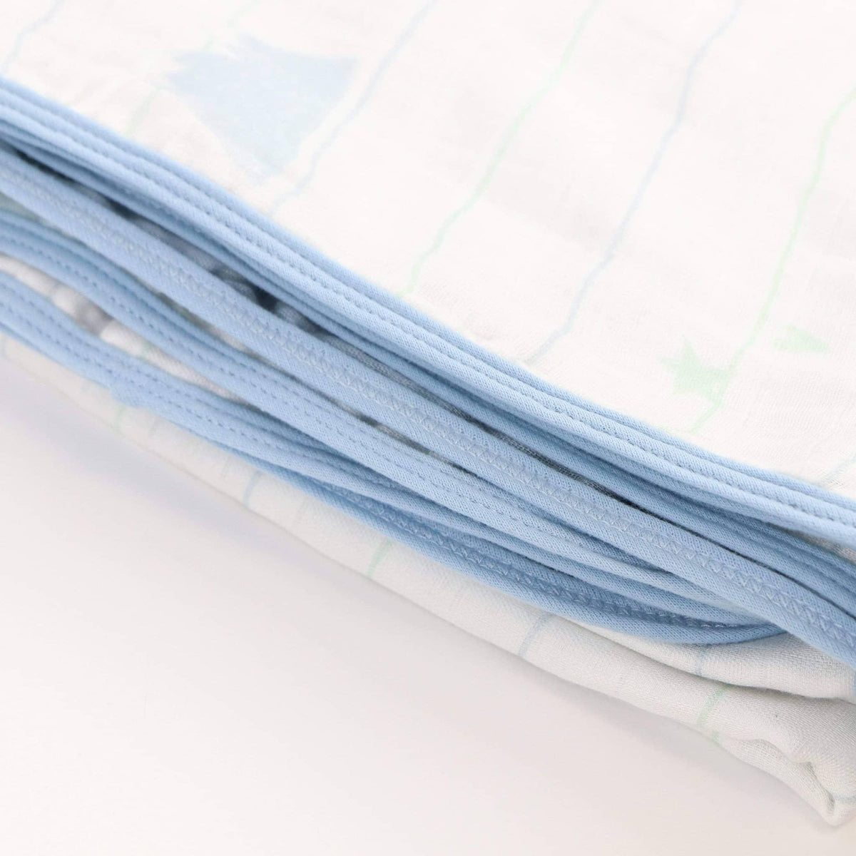 Folded white and blue bamboo muslin baby blanket with soft pastel star and stripe pattern for newborns