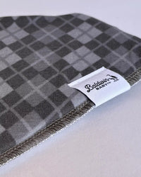 Gray checkered timeless charm bandana bib with Baldwin Baby Co label, classic pattern offering drool protection and stylish baby accessory.