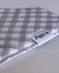Gray and white gingham bandana bib with visible Baldwin Baby Co label, showcasing classic pattern and detailed stitching.