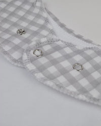 Gray and white gingham baby bandana bib with metal snap buttons and soft hemmed edges for classic style and drool protection.