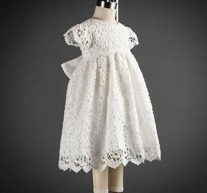 White baby baptism gown with intricate lace overlay and short puff sleeves