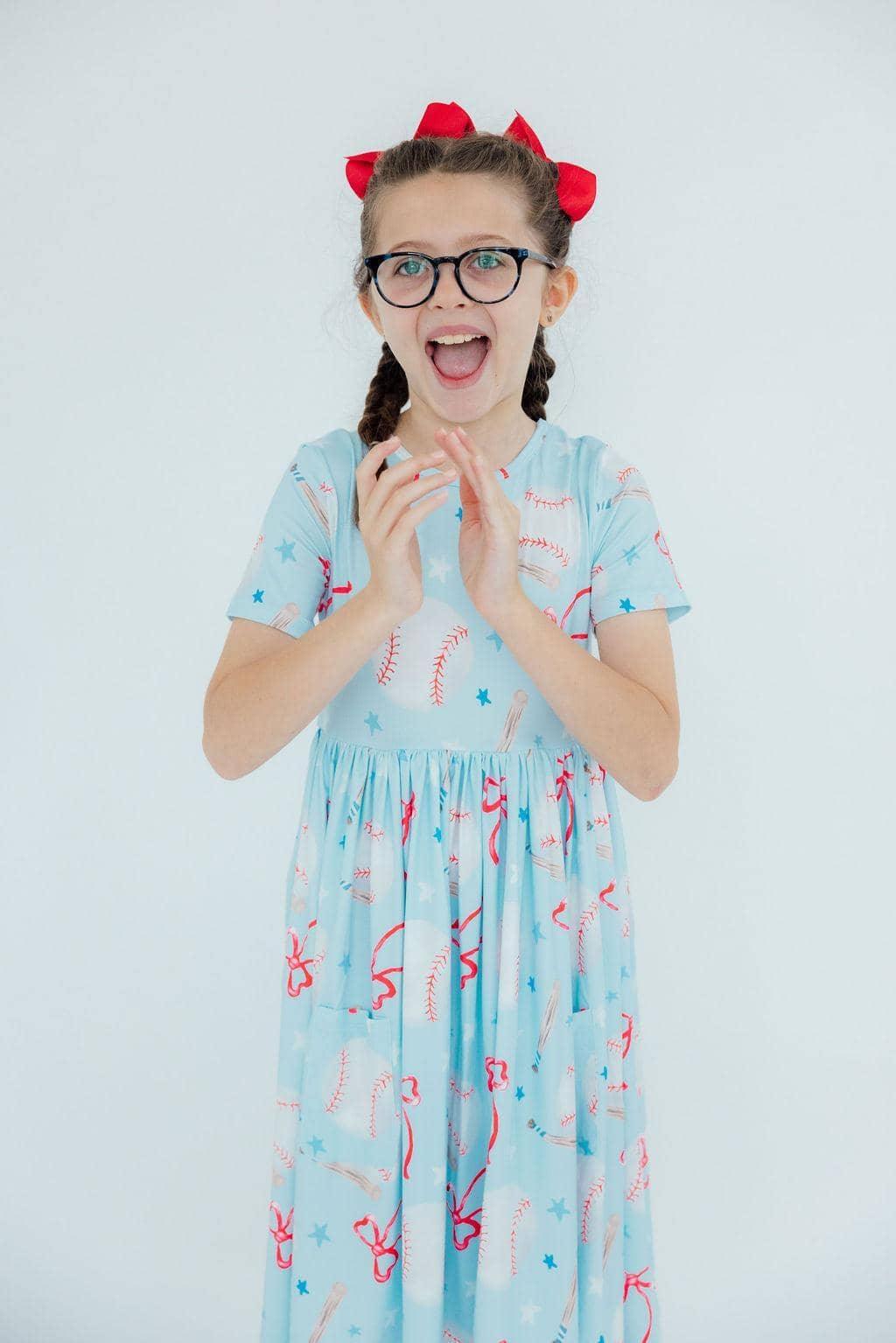 Girls light blue short sleeve twirl pocket dress with baseball print and red bows in hair baseball twirl dress for girls
