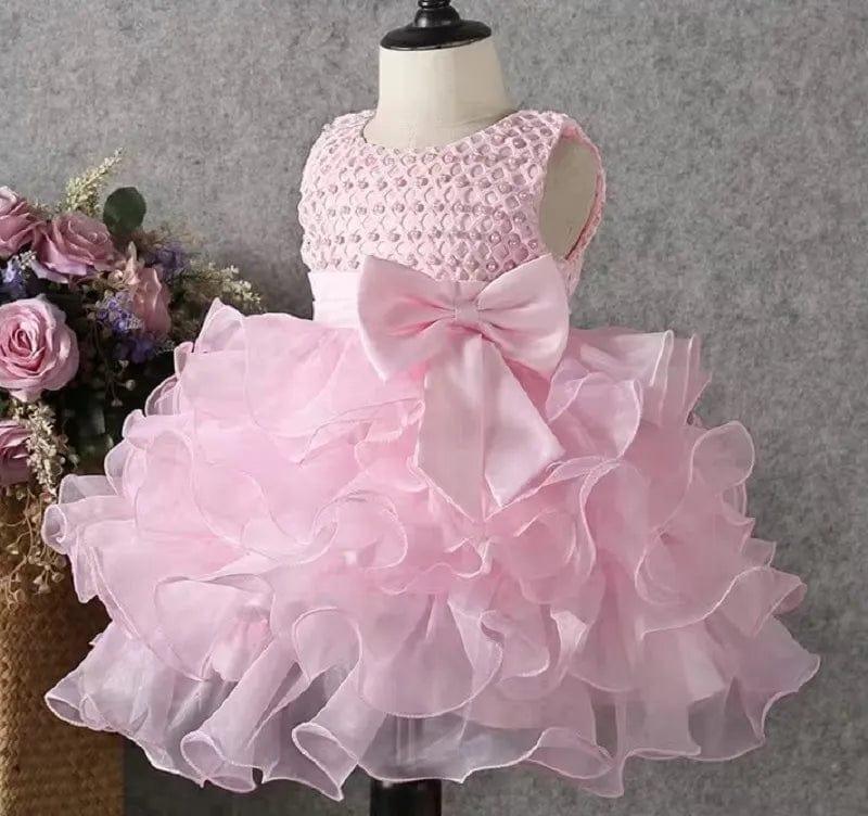 pink beaded special occasion dress for girls sized toddler displayed on mannequin with large bow and ruffled skirt