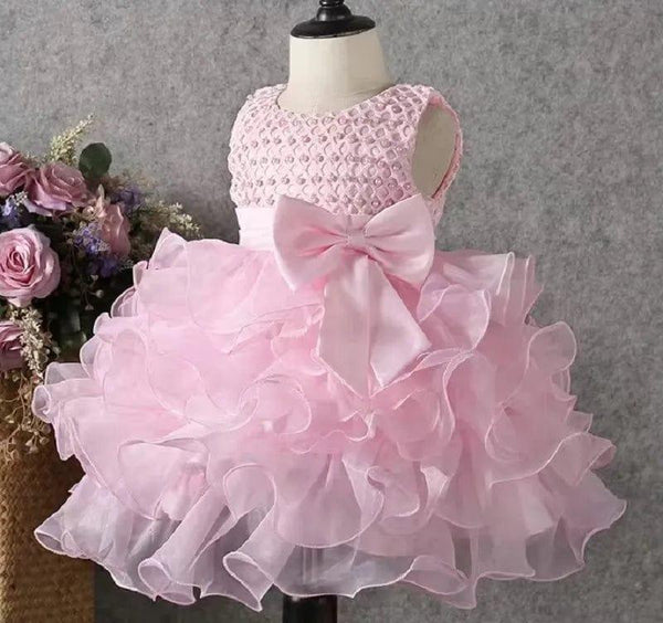 pink beaded special occasion dress for girls sized toddler displayed on mannequin with large bow and ruffled skirt