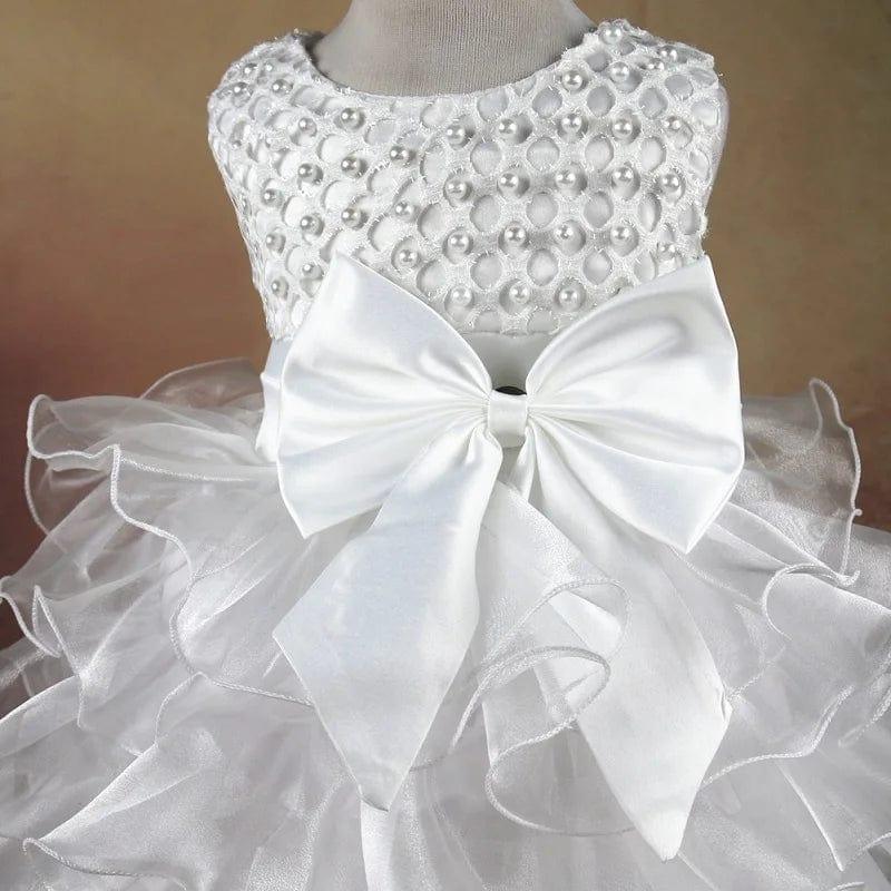 white beaded special occasion dress for girls with large bow and layered skirt on mannequin