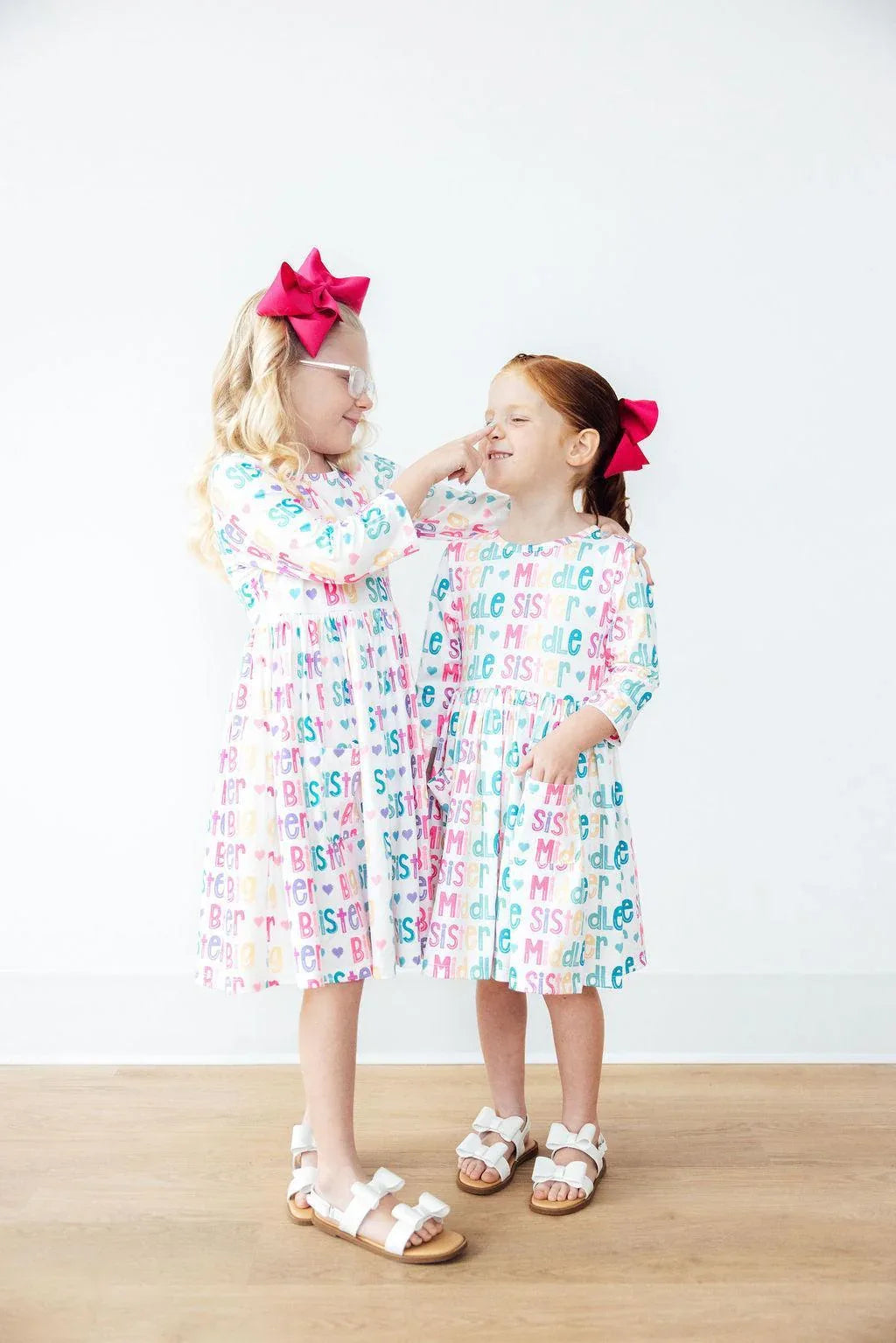 Two girls wearing colorful big sister dress for girls with sleeves smiling and interacting indoors