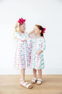 Two girls wearing colorful big sister dress for girls with sleeves smiling and interacting indoors