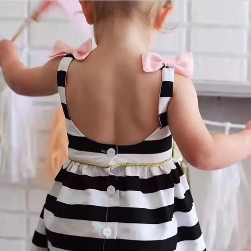 toddler girl wearing black and white striped dress for girls with pink bows playing with ribbons