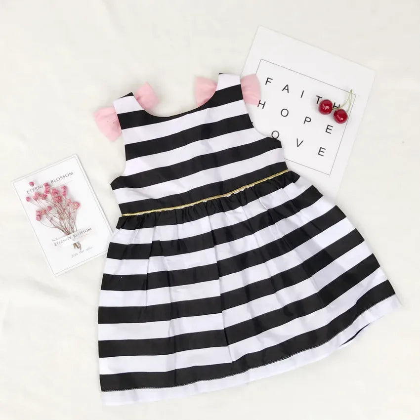 black and white striped dress for girls with pink bow sleeves laid flat on white background