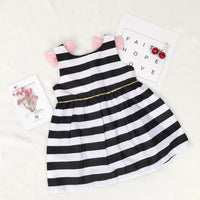 black and white striped dress for girls with pink bow sleeves laid flat on white background