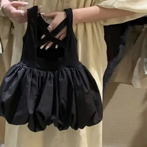 close up of black girls party dress with cutouts held by adult hand showing crisscross straps