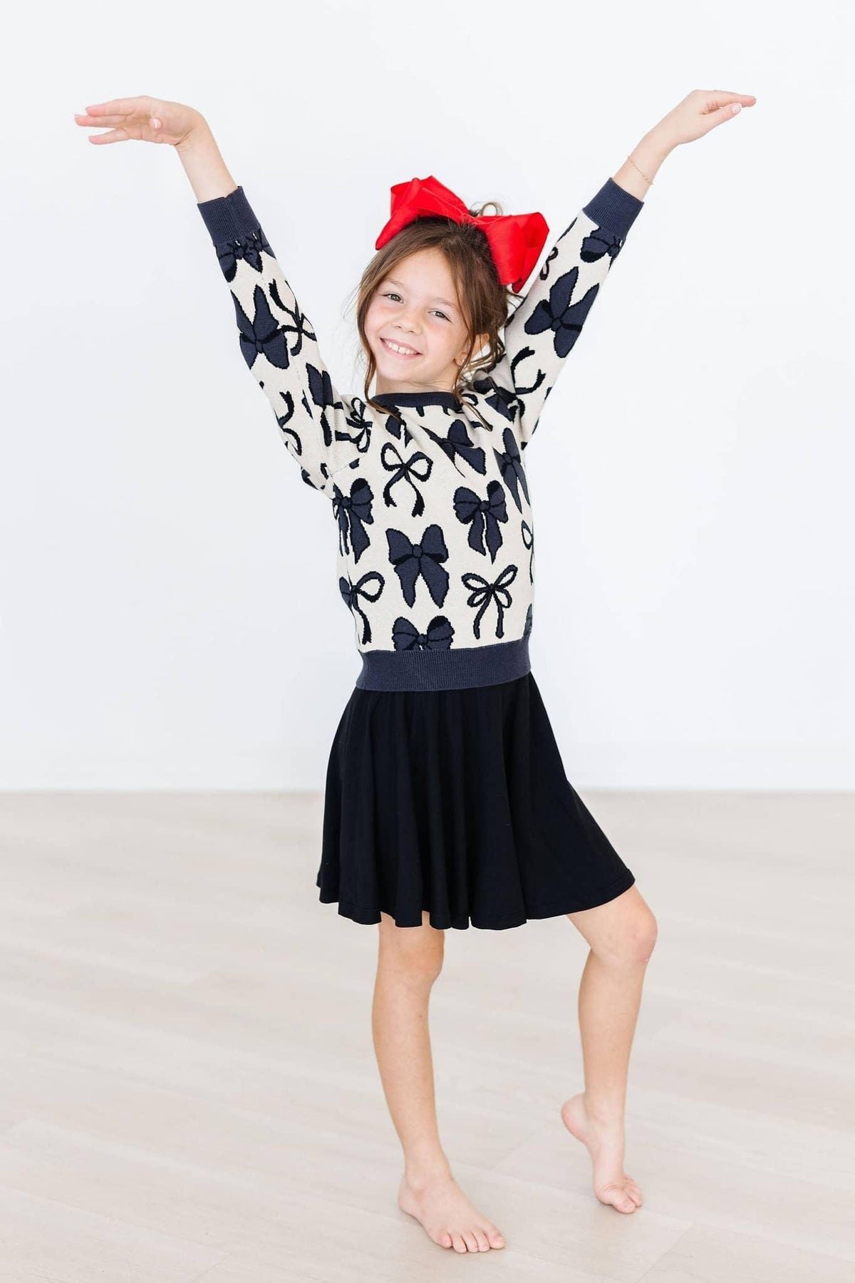 young girl wearing black twirl skort for girls smiling with arms raised in dance pose