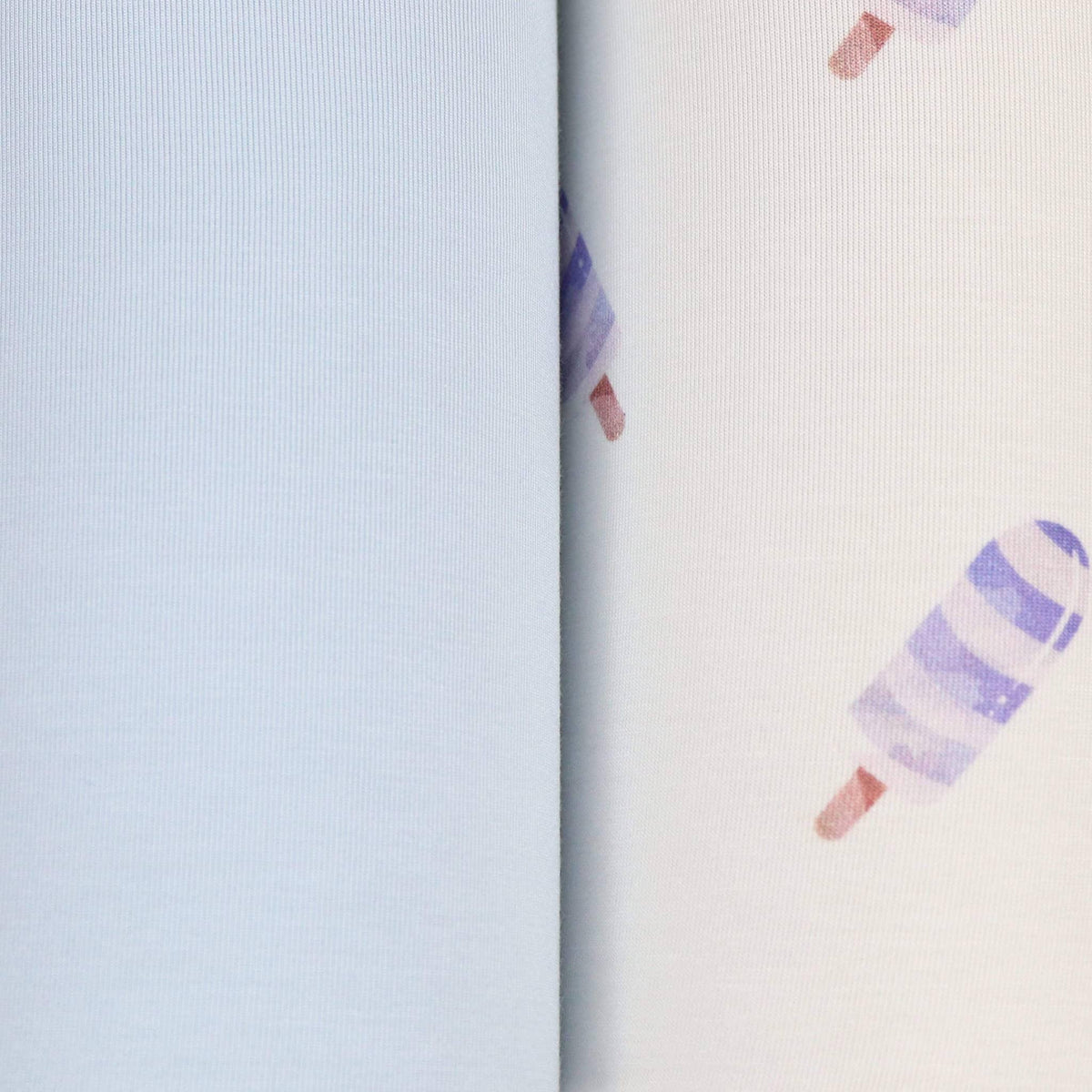 Close-up of blue baby swaddle blanket set showing solid light blue fabric and white fabric with purple popsicle print for newborns