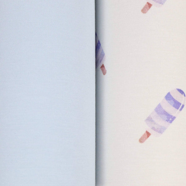 Close-up of blue baby swaddle blanket set showing solid light blue fabric and white fabric with purple popsicle print for newborns