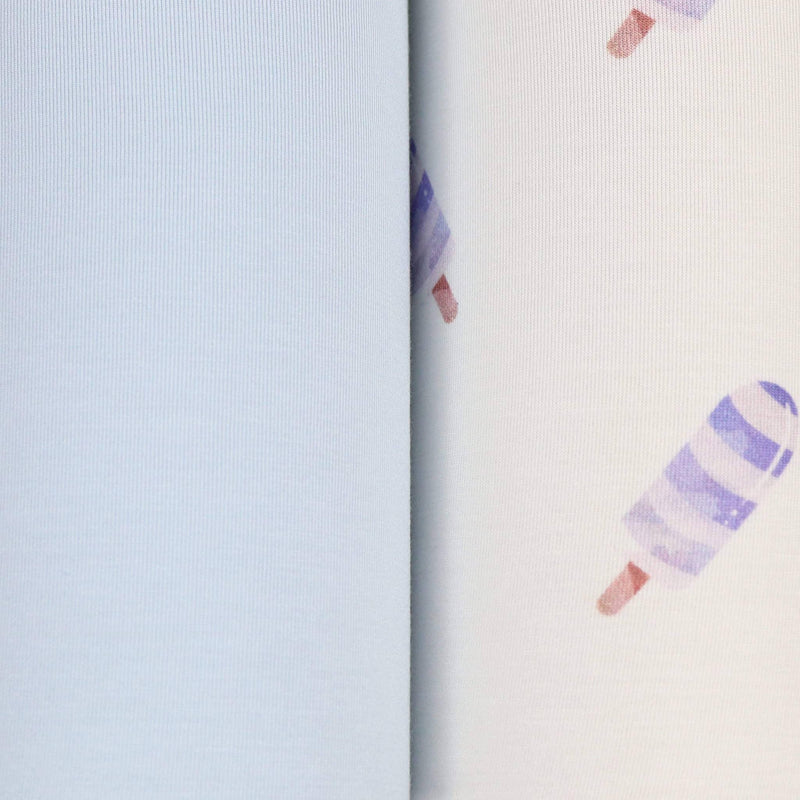 Close-up of blue baby swaddle blanket set showing solid light blue fabric and white fabric with purple popsicle print for newborns