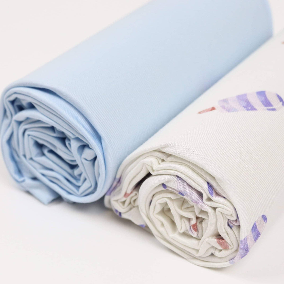 blue baby swaddle blanket set with solid blue and patterned white blankets rolled for newborns