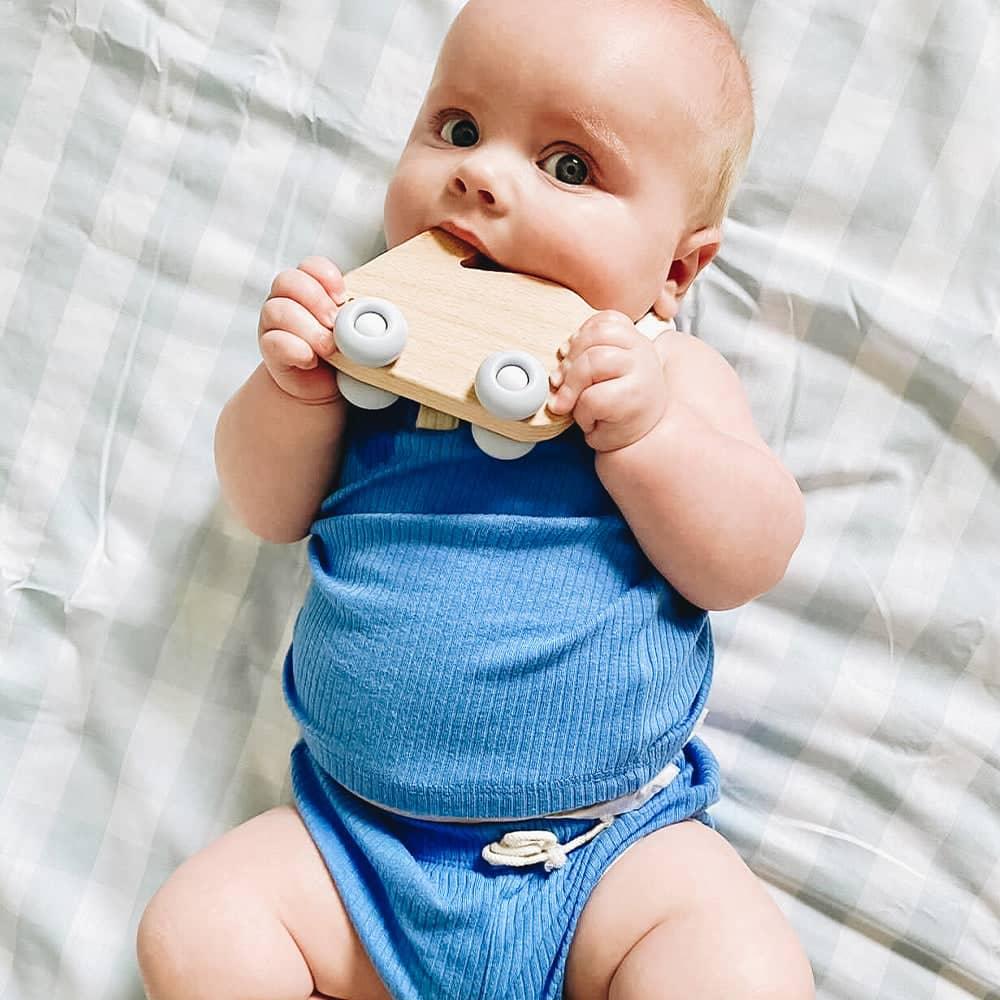 Baby in blue outfit chewing on natural wood and white silicone blue bunny silicone wood teether
