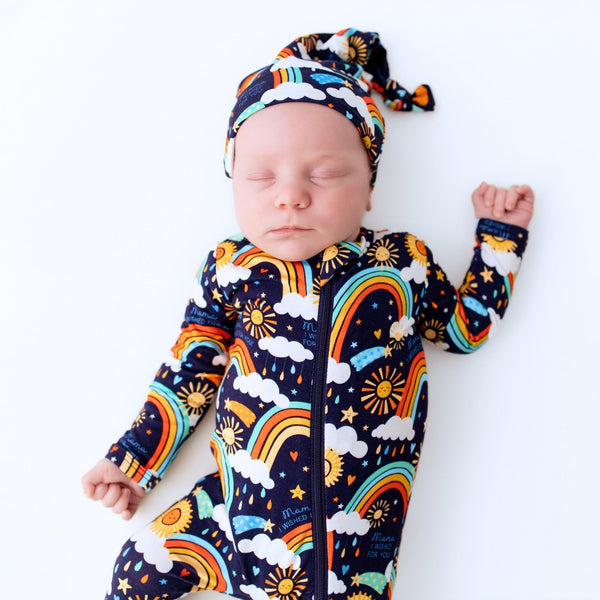 Baby sleeping in blue footie with rainbow sun and cloud print; features phrase 'Mama, I Wished for You'.