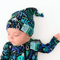 Newborn wearing The SoftKnot Cap by Mystic Mama Blue featuring a blue-green botanical print.