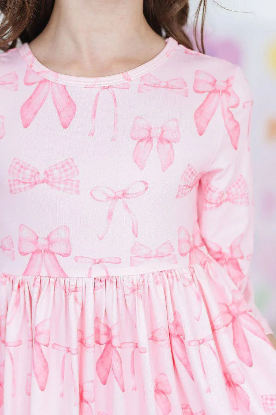 Close-up of girl wearing Mila & Rose blushing bows twirly dress for girls in soft pink with 3/4 sleeves