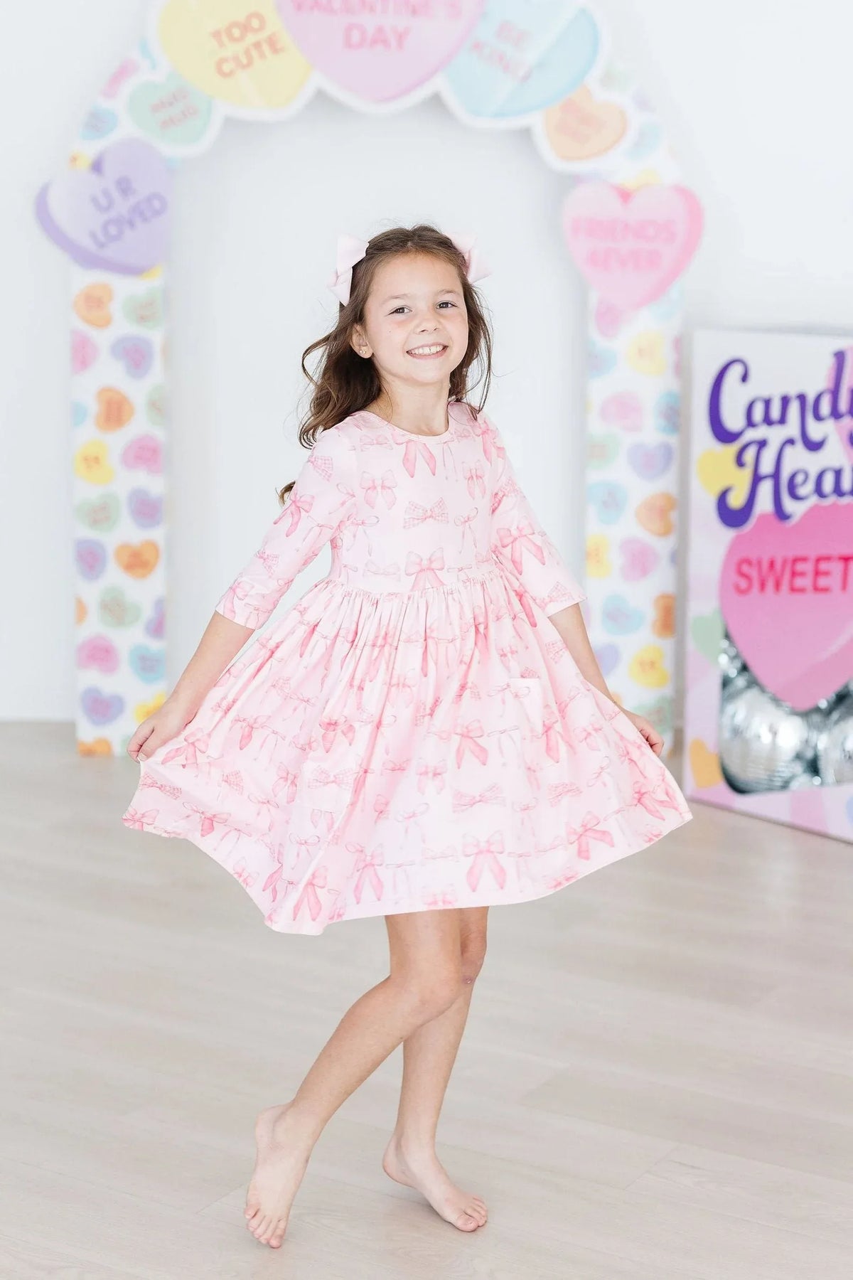 young girl wearing blushing bows twirly dress for girls in light pink posing while twirling