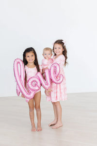 Two girls in pink blushing bows twirly dress for girls holding love balloon and baby in matching outfit