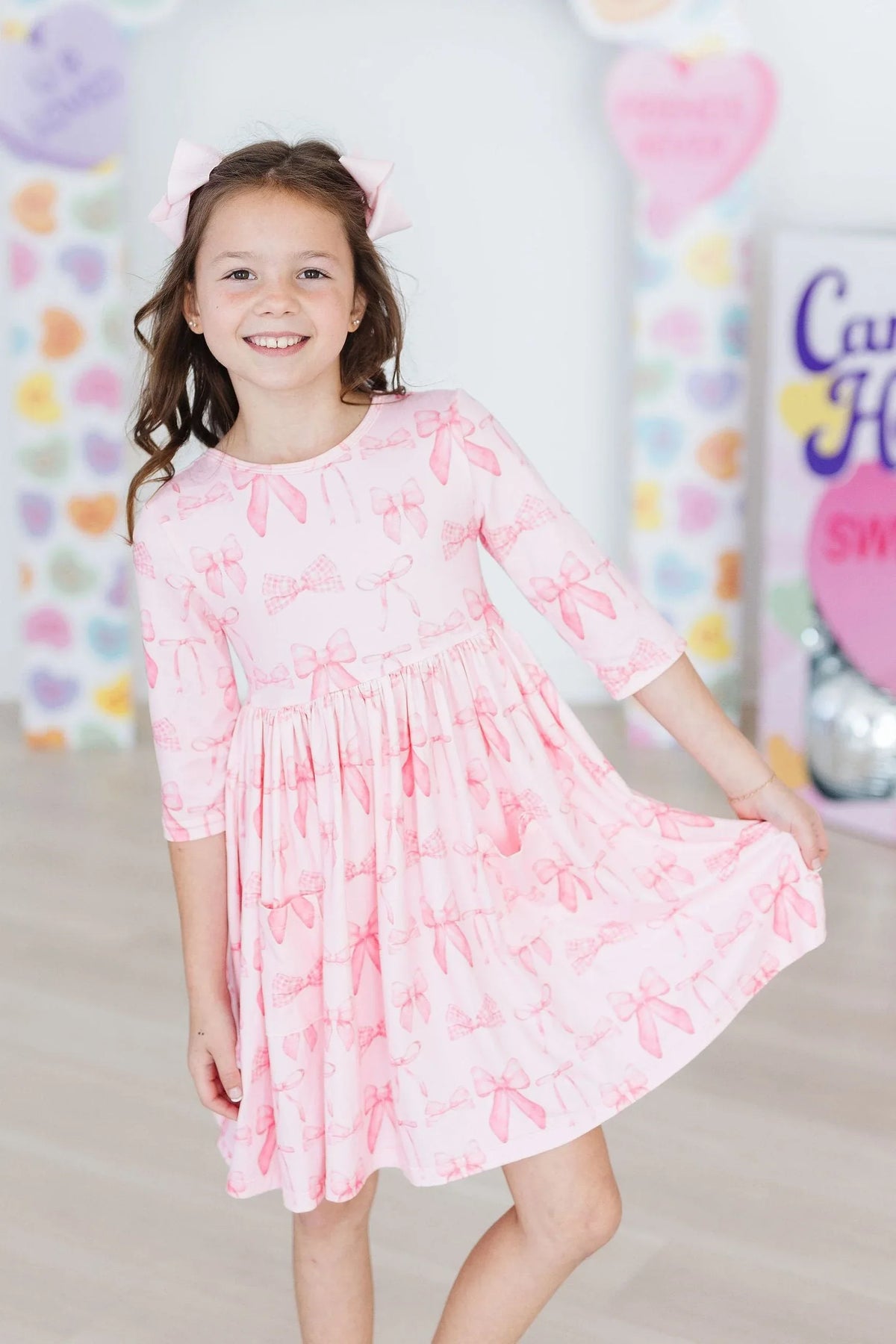 girl wearing pink blushing bows twirly dress for girls holding the skirt while smiling