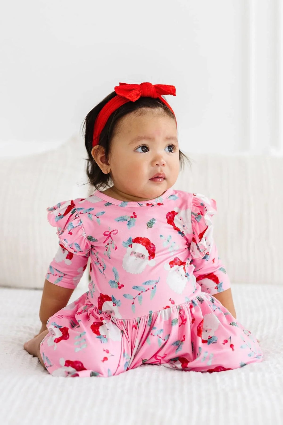 baby girl wearing pink Twirl Bodysuit for baby girls flutter sleeves sitting on bed