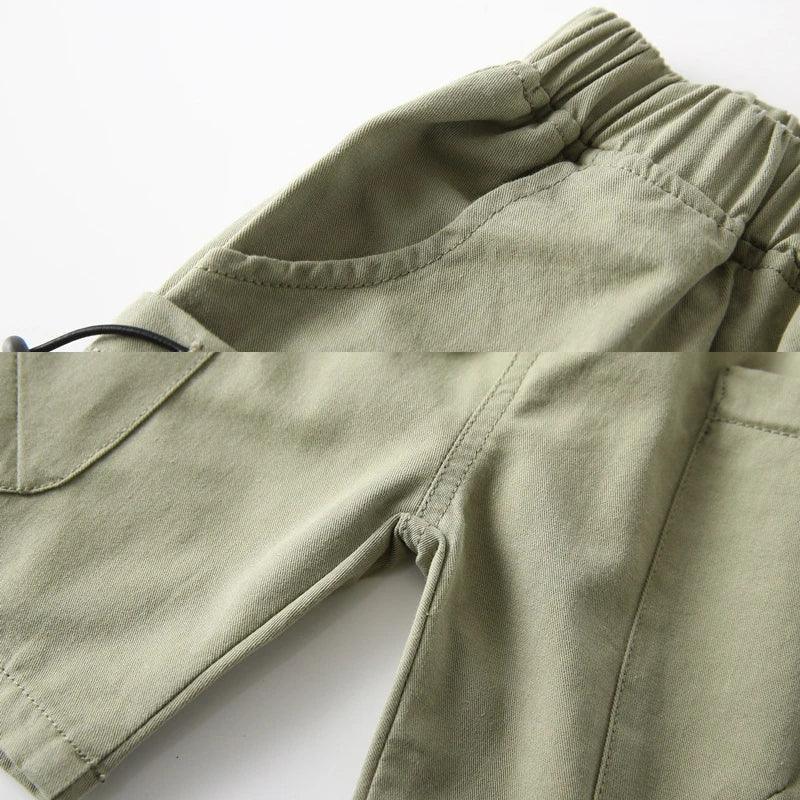 close-up of olive green boys cargo shorts with pockets for toddlers showing elastic waistband and side pocket details