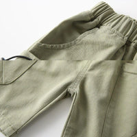 close-up of olive green boys cargo shorts with pockets for toddlers showing elastic waistband and side pocket details