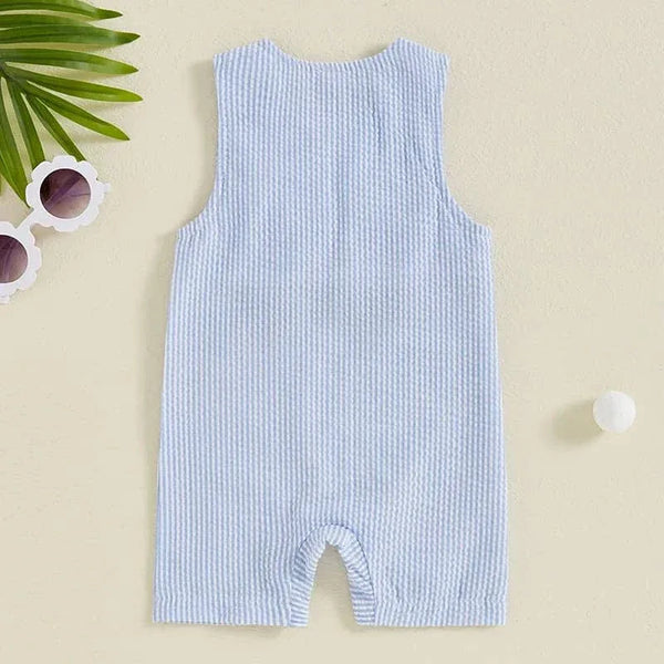 light blue striped boys golf romper for infants laid flat on beige surface with sunglasses and leaf