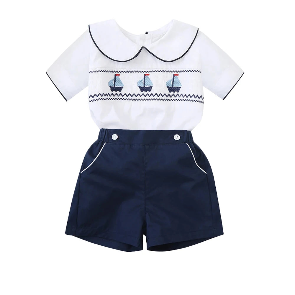 White cotton boys smocked sailboat outfit with navy blue shorts and sailboat embroidery