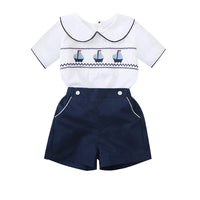 White cotton boys smocked sailboat outfit with navy blue shorts and sailboat embroidery