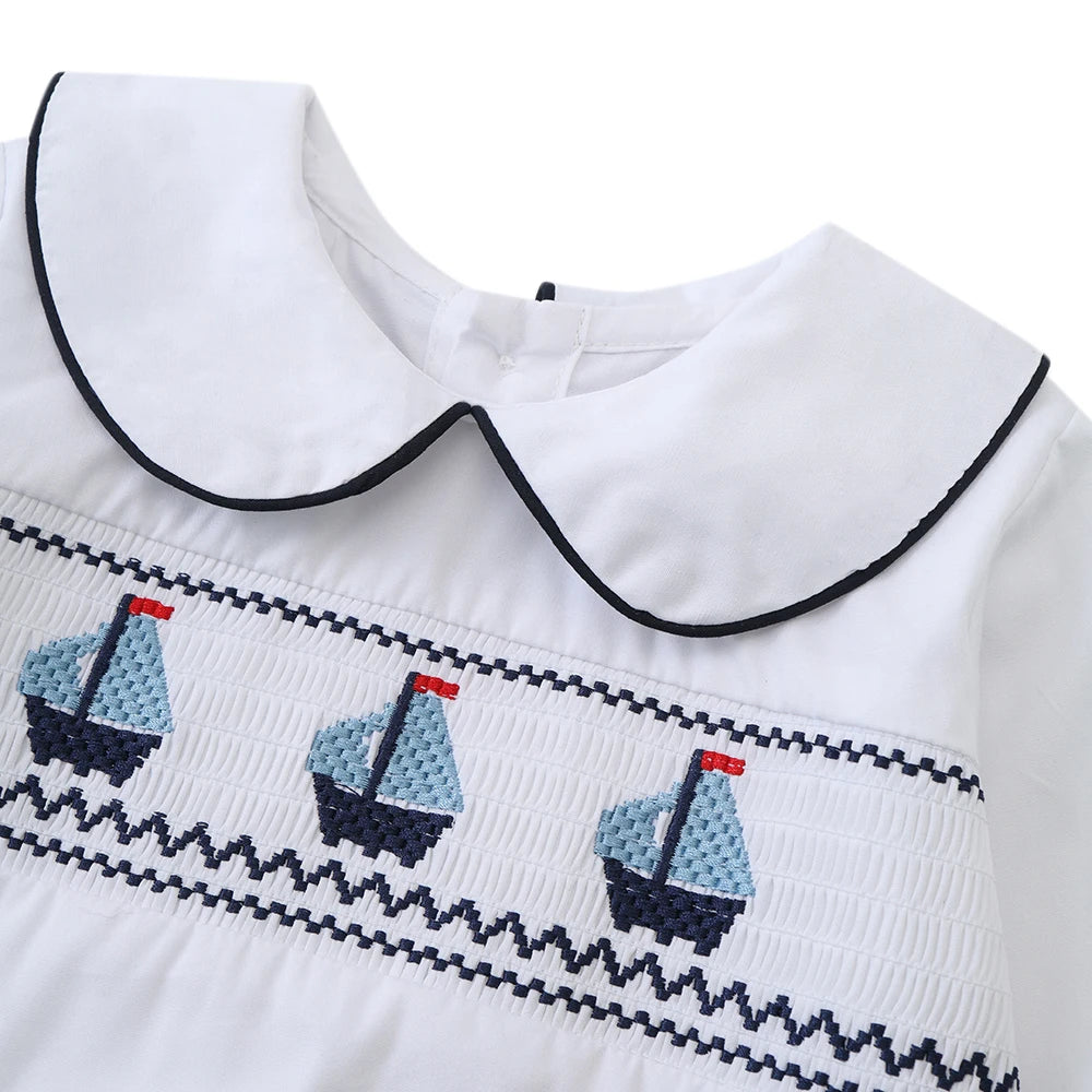 White cotton boys smocked sailboat outfit with navy blue and light blue sailboat embroidery and peter pan collar