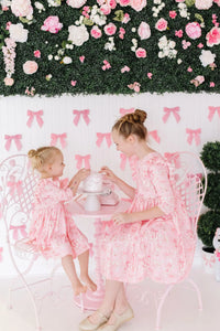 Bubble gum pink girls ruffle dress twirl style in 3 4 length worn by two girls with floral backdrop