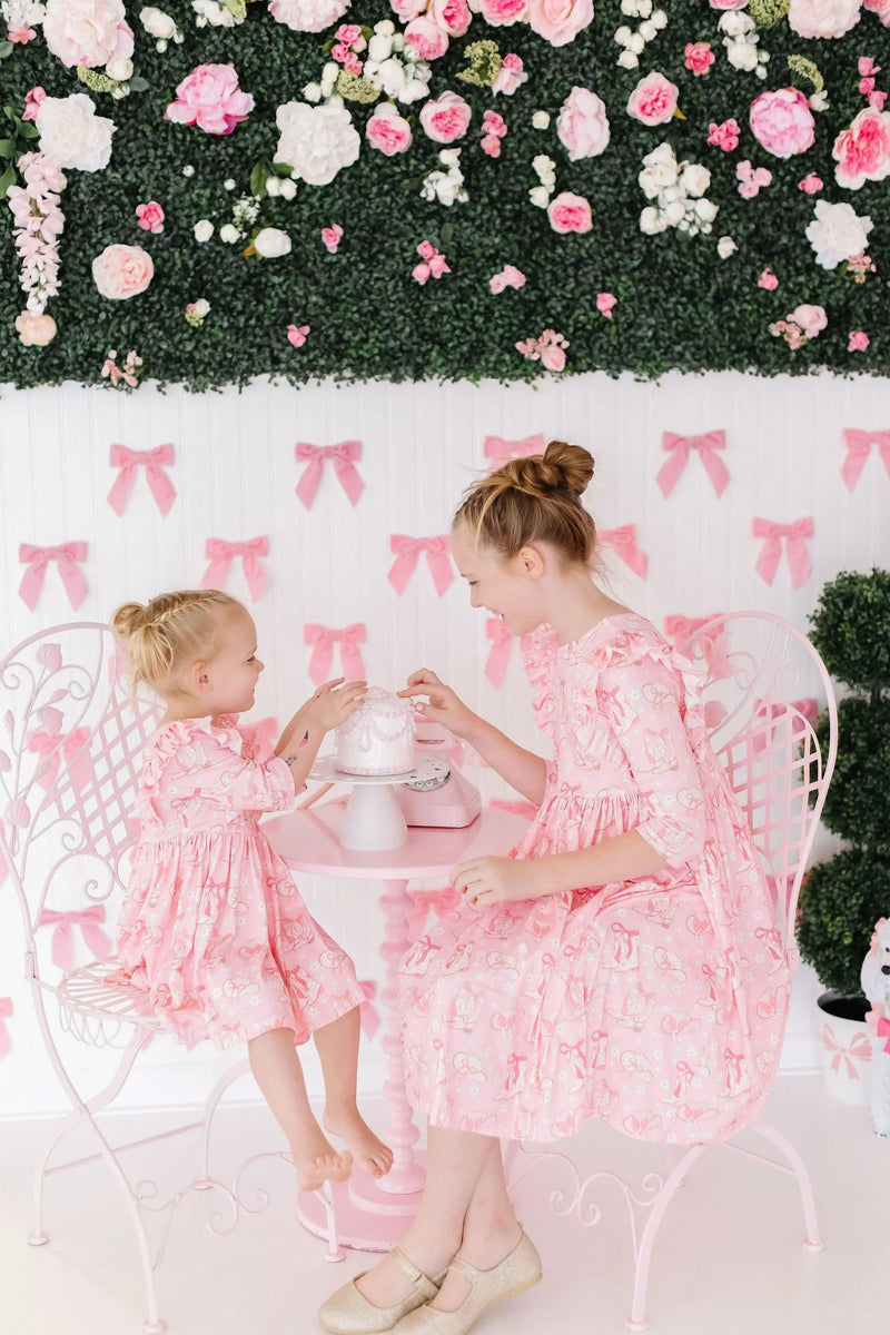 Bubble gum pink girls ruffle dress twirl style in 3 4 length worn by two girls with floral backdrop