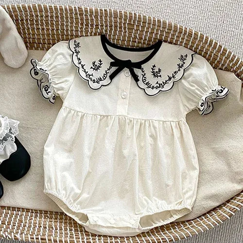 Ivory bubble romper for babies with black embroidered collar and puff sleeves