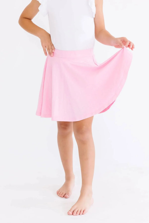 Girl wearing bubblegum pink twirl skort for girls holding the skirt while standing barefoot