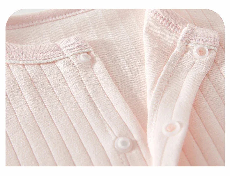 Close-up of baby pink bunny baby romper with ribbed texture and snap button closure for infants