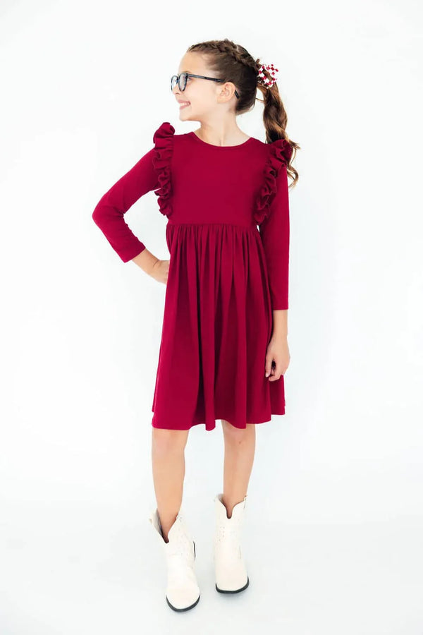 Girl wearing burgundy ruffle twirl dress for girls standing with hand on hip and smiling