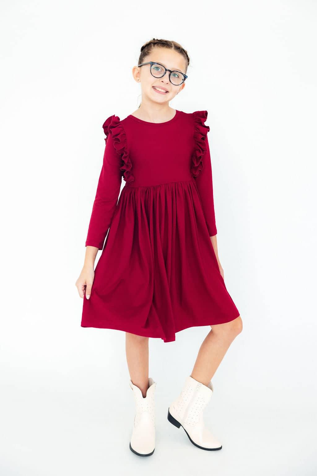 young girl wearing burgundy ruffle twirl dress for girls standing and posing with white boots