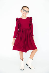 young girl wearing burgundy ruffle twirl dress for girls standing and posing with white boots