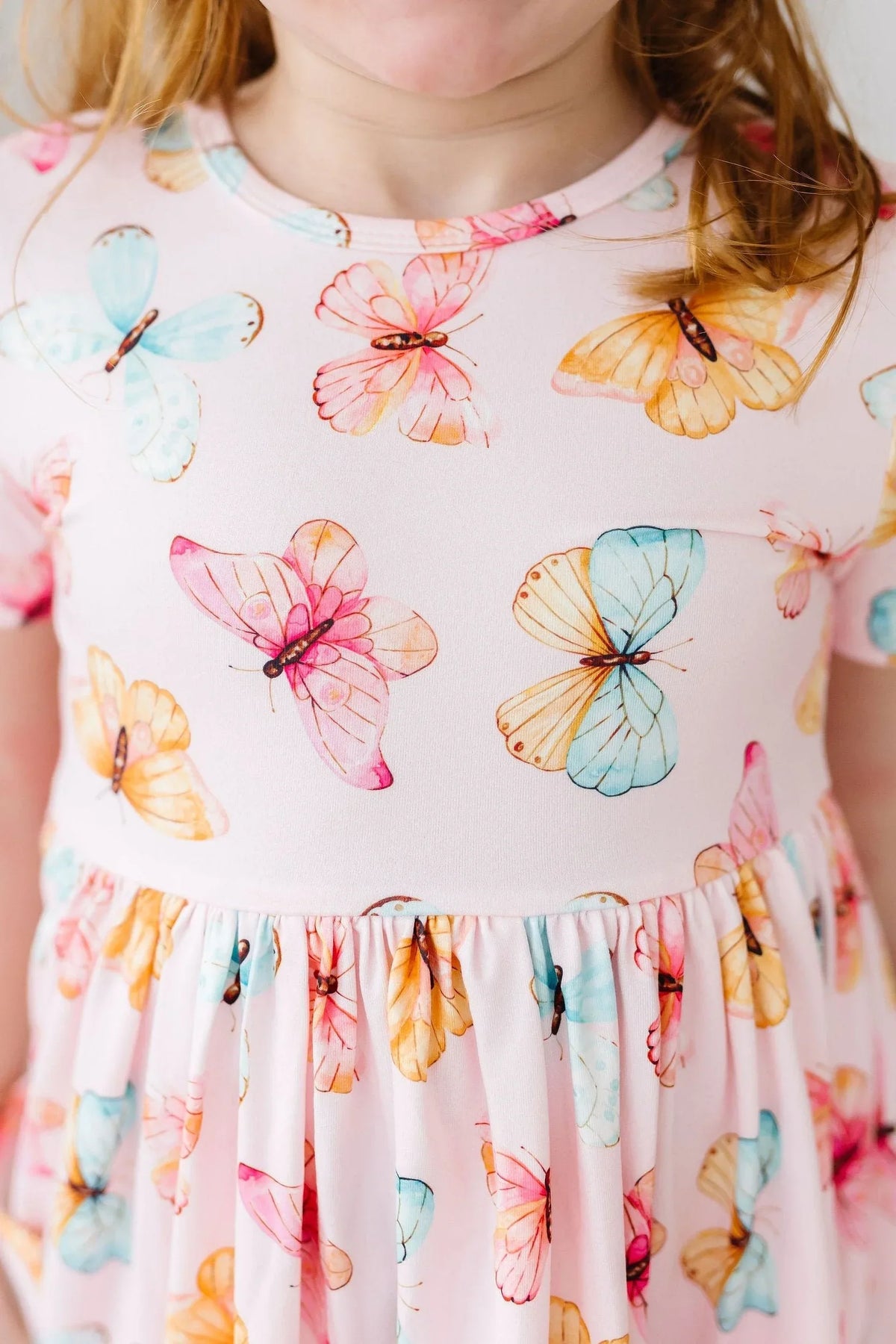 close-up of girl wearing pink butterfly print twirl dress for girls showing colorful butterfly pattern